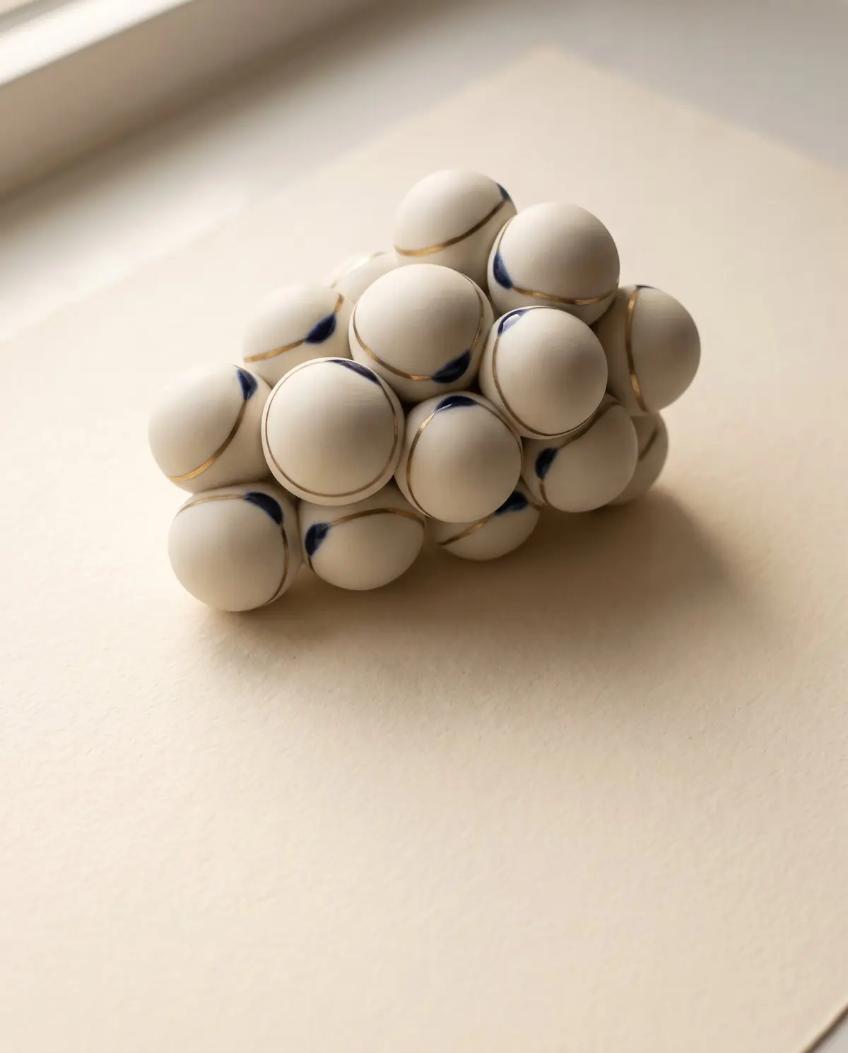 Escultura em porcelana de células de gordura, com detalhes em azul-marinho e latão